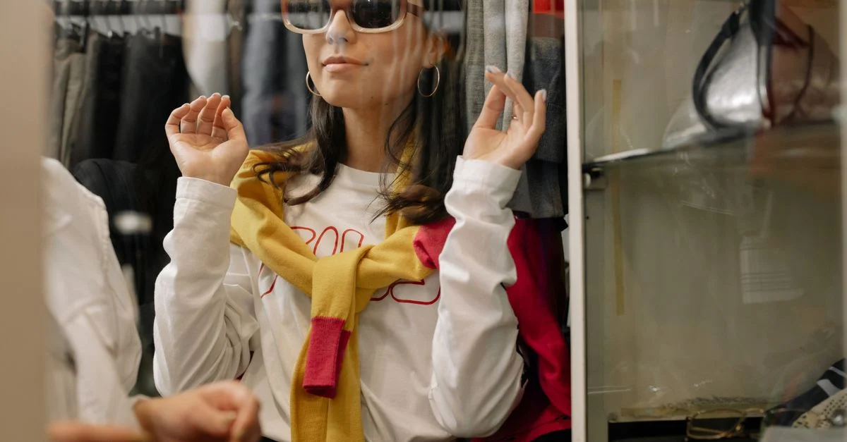 Mujer elegante en una boutique probándose gafas de sol, reflejando elecciones de moda modernas.