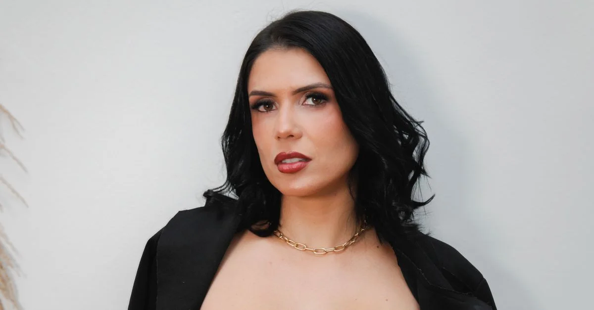 Retrato de una mujer elegante con cabello oscuro, vestida con un traje negro.