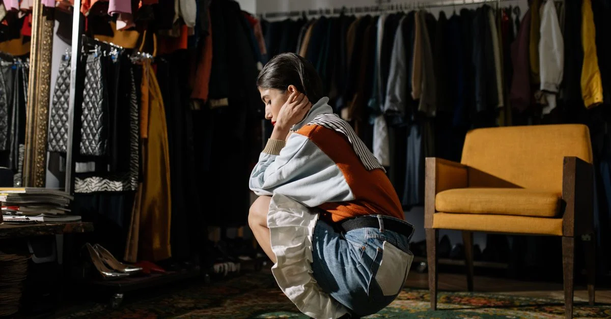 Una mujer elegante posando de manera pensativa en una tienda de ropa vintage, mostrando moda retro.