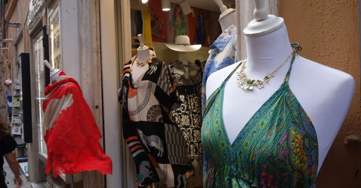Maniquíes adornados con coloridos vestidos de verano y bufandas en el escaparate de una boutique.