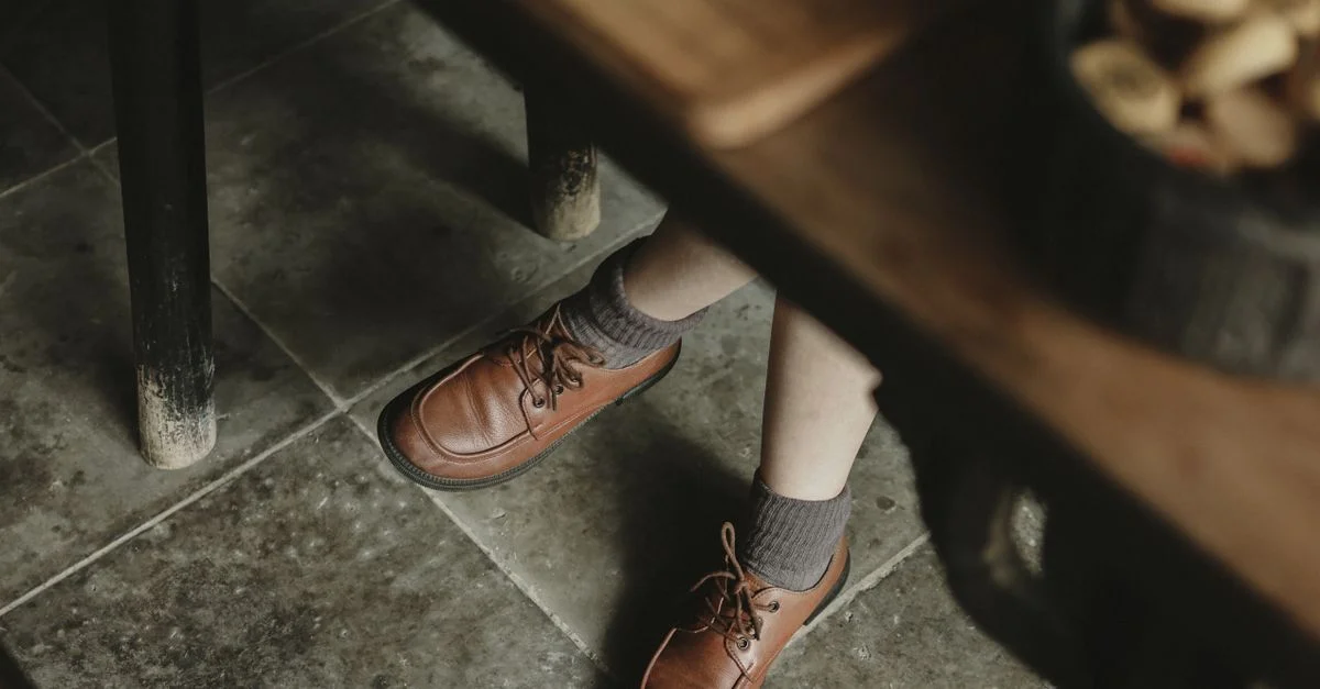 Primer plano de piernas con zapatos de cuero en un entorno interior.