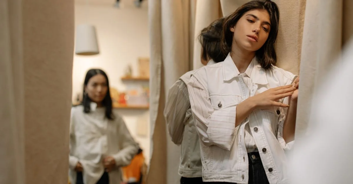 Mujer en un probador de tienda de segunda mano disfrutando de su experiencia de compras vintage.