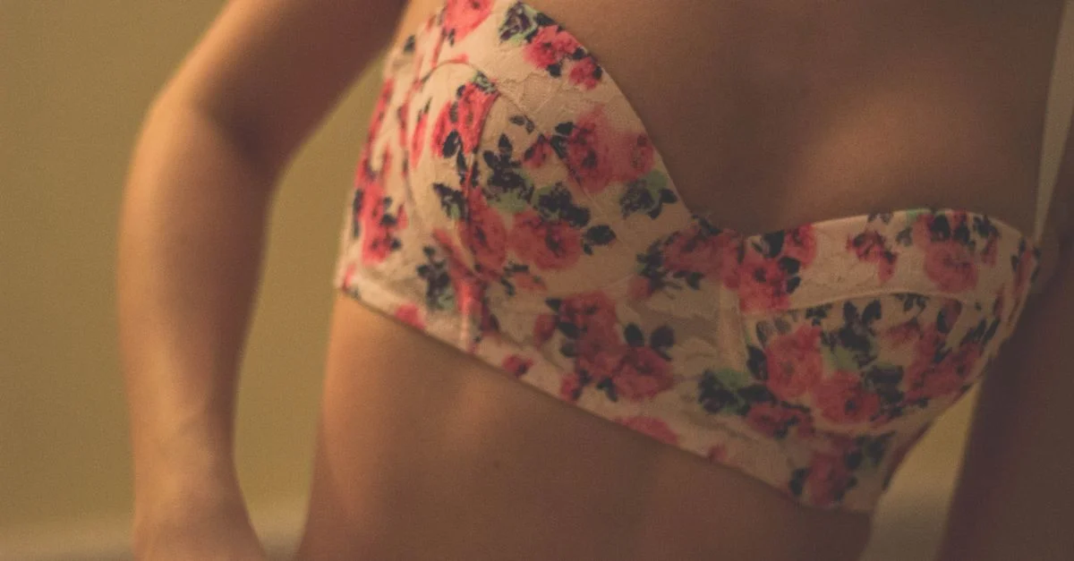 Primer plano íntimo de una mujer usando un sujetador de estampado floral en interiores. La iluminación suave realza el ambiente.