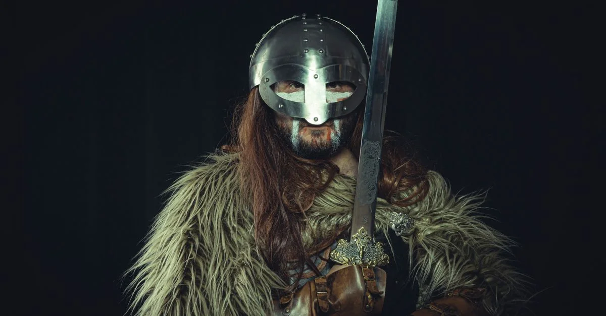 Guerrero vikingo con armadura, casco y espada, evocando tiempos medievales.