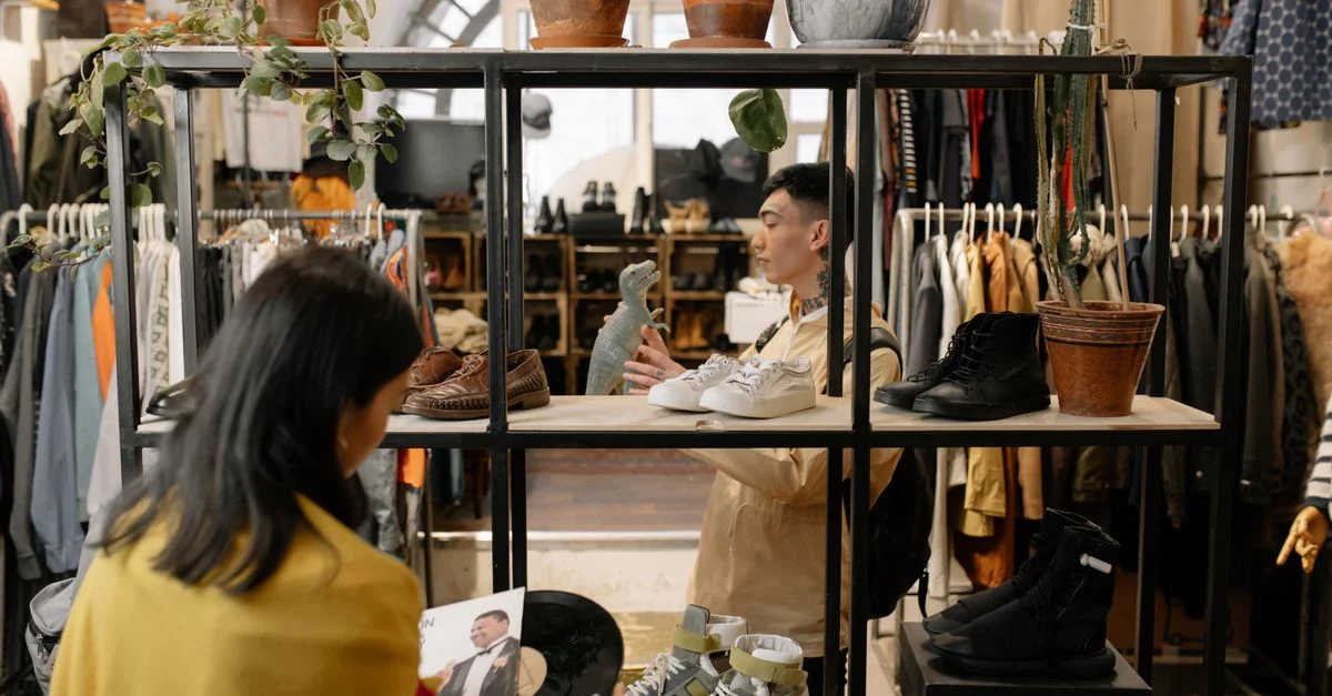 Personas navegando y seleccionando artículos en el interior de una tienda de ropa vintage con estilo.